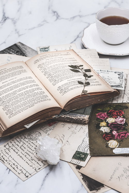 古びた洋書と絵はがき、コーヒーのある静物