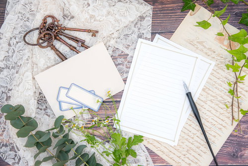 木製デスクに置かれたアンティークキーと便箋