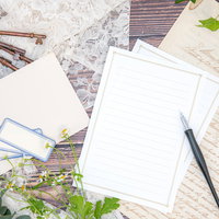 白い便箋に向かう万年筆とデスクの情景、観葉植物のあるオフィスの写真