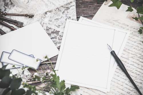 デスクに置かれた便箋と英文の手紙、アンティークキーとペン