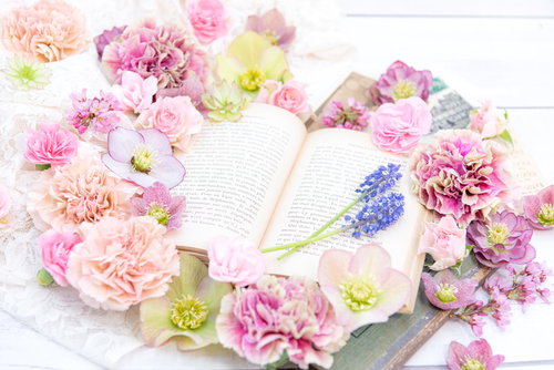 色とりどりの生花に包まれた洋書と手紙のフラワーアレンジメント