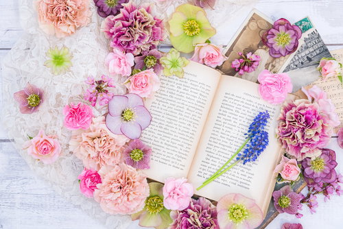 春の花と洋書が散らばるカラフルなデスク上の華やかなフラットレイ