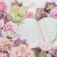 ピンクと紫の花に包まれた洋書のフラットレイの写真