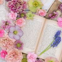 薔薇やカラフルな春の花に囲まれた洋書と雑貨の写真