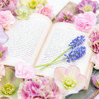 多種の生花に彩られた洋書の上のアレンジメントの写真