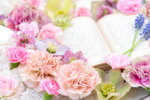 デスクの洋書の周りに散らばるピンク色の薔薇