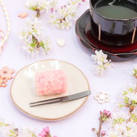 木製のお皿に盛られたピンク色の練りきりと抹茶の和菓子セットの写真