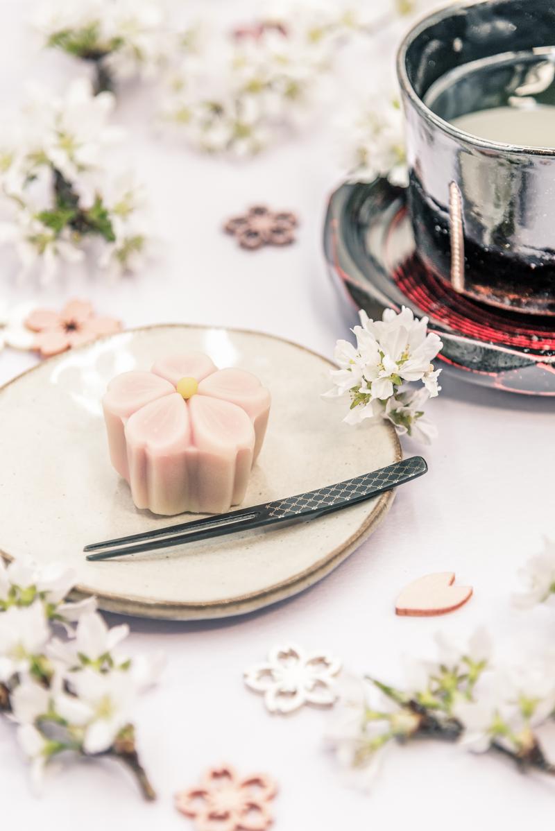 白い皿に乗せたピンク色の花形練り切りと抹茶の茶碗のティータイム