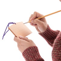 赤いセーターを着た男性が筆で絵馬に願い事を書き込むの写真