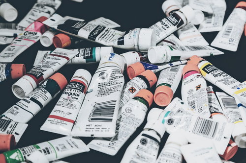 白や赤、黒などのチューブ絵の具が雑多に置かれた画材