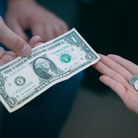 1ドル札と160円硬貨を手渡しで交換する場面の写真