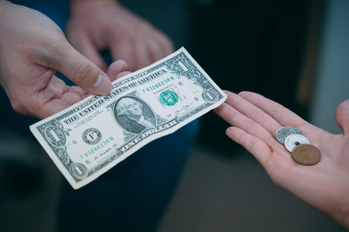 1ドル札と160円硬貨を手渡しで交換する場面