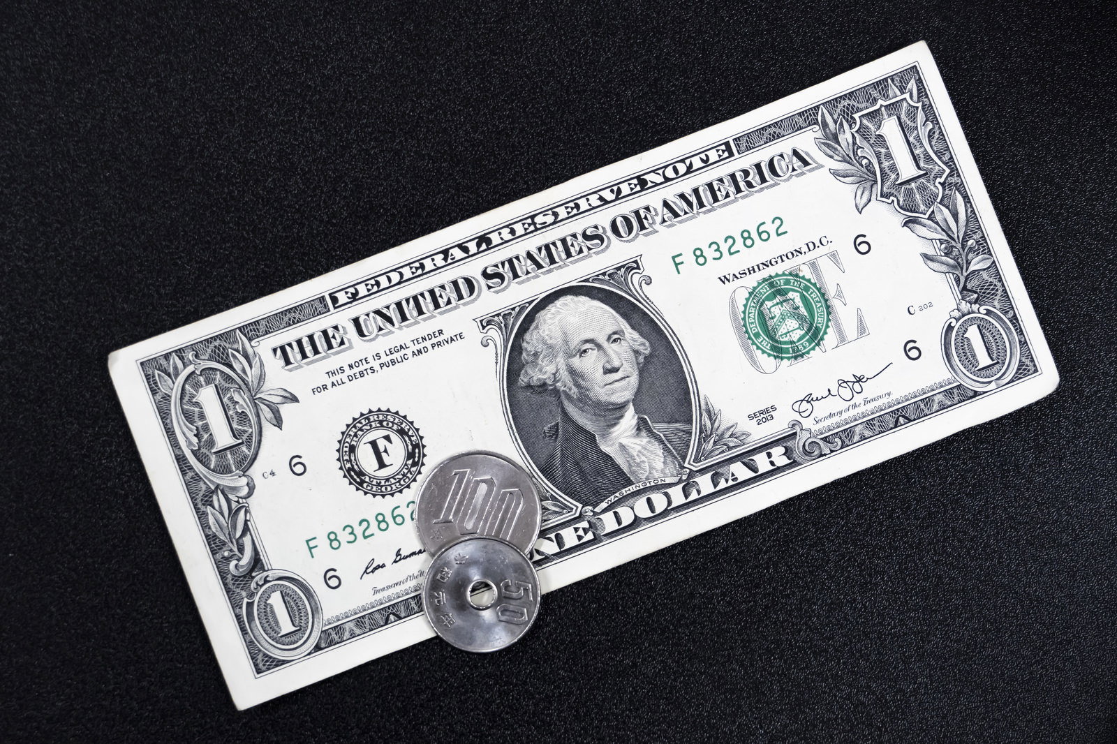 黒い背景に置かれた1ドル紙幣と硬貨