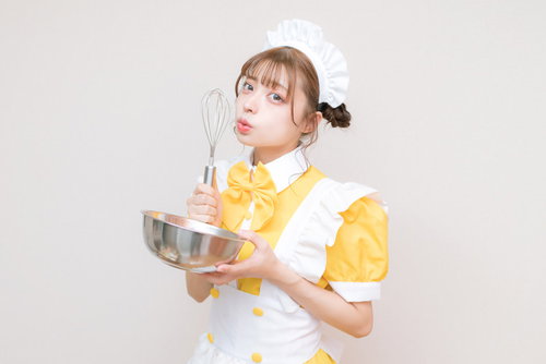 黄色のメイド服でホイッパーを持ったコスプレ女性