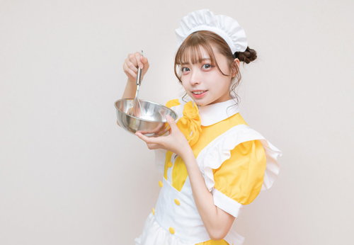 白いエプロンのメイド服でボールとホイッパーを使う女性