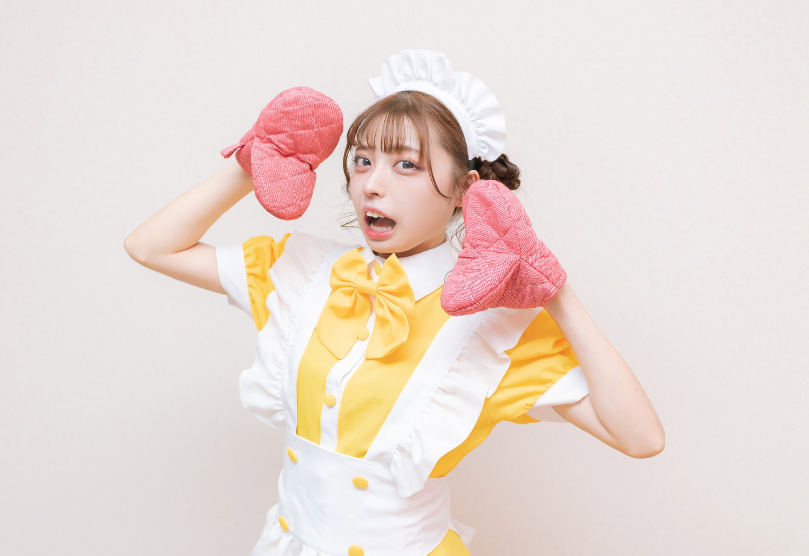 ピンクの鍋つかみを手にして大きく口を開けて驚くメイド服の女性［モデル：高尾実生］