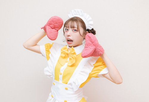 ピンクの鍋つかみを手にして驚くメイド服の女性