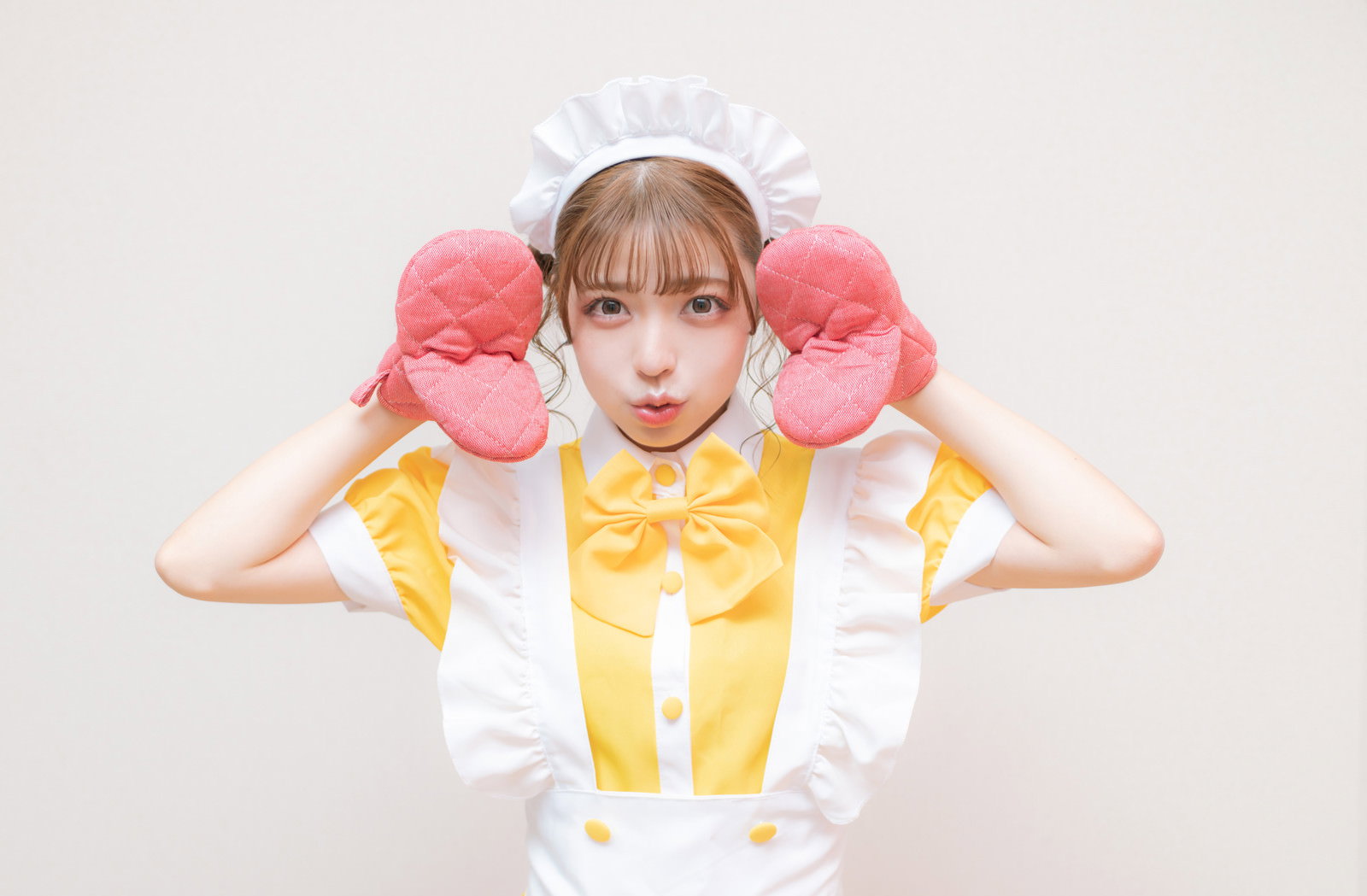 ピンクのミトンを両手につけたメイド服姿の女性［モデル：高尾実生］