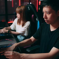 真剣な眼差しでゲームに没頭するカップル、ヘッドセット装着で対戦中の写真