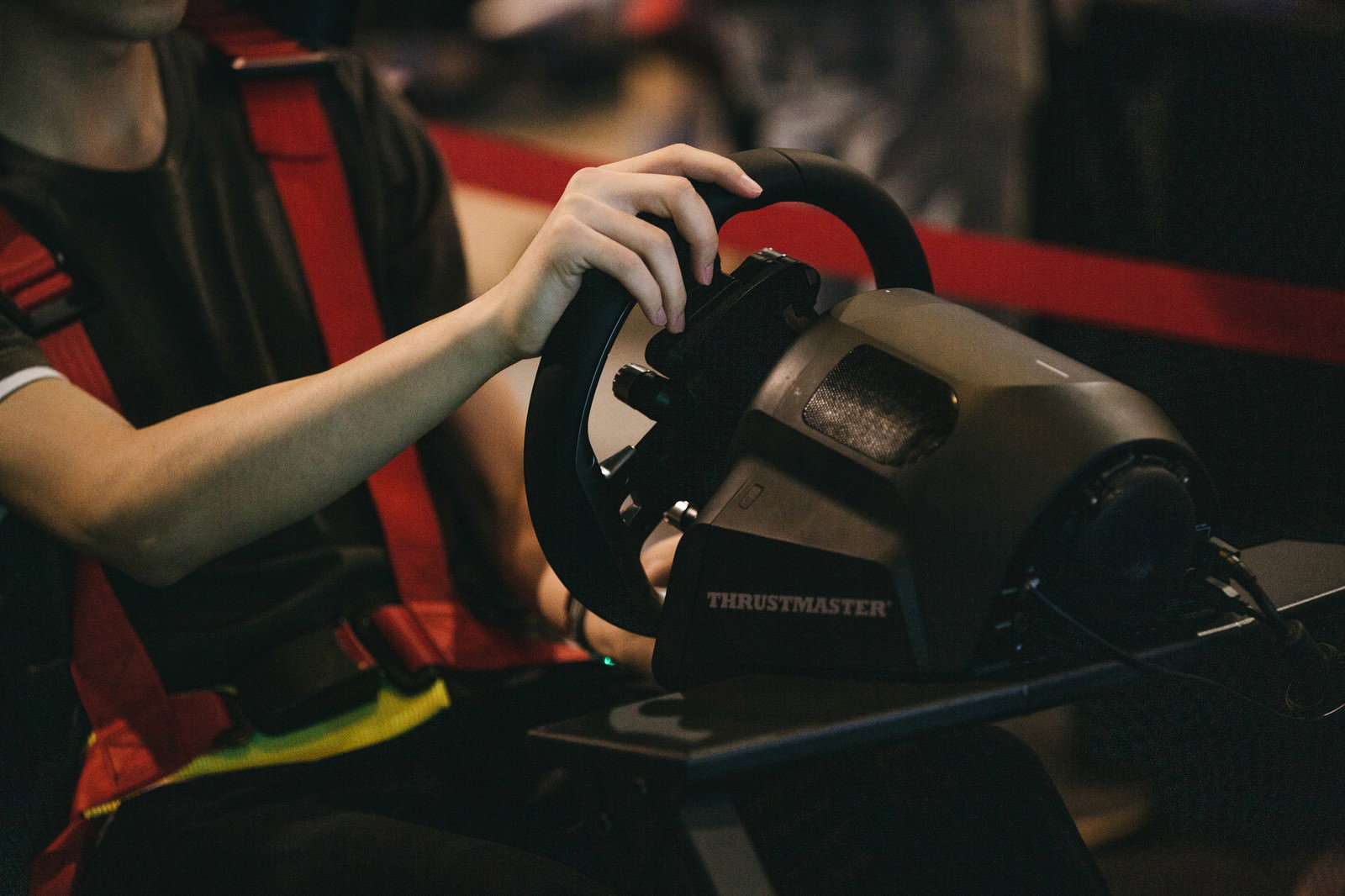 レースゲームの黒いハンドルコントローラーを両手で握っている手元