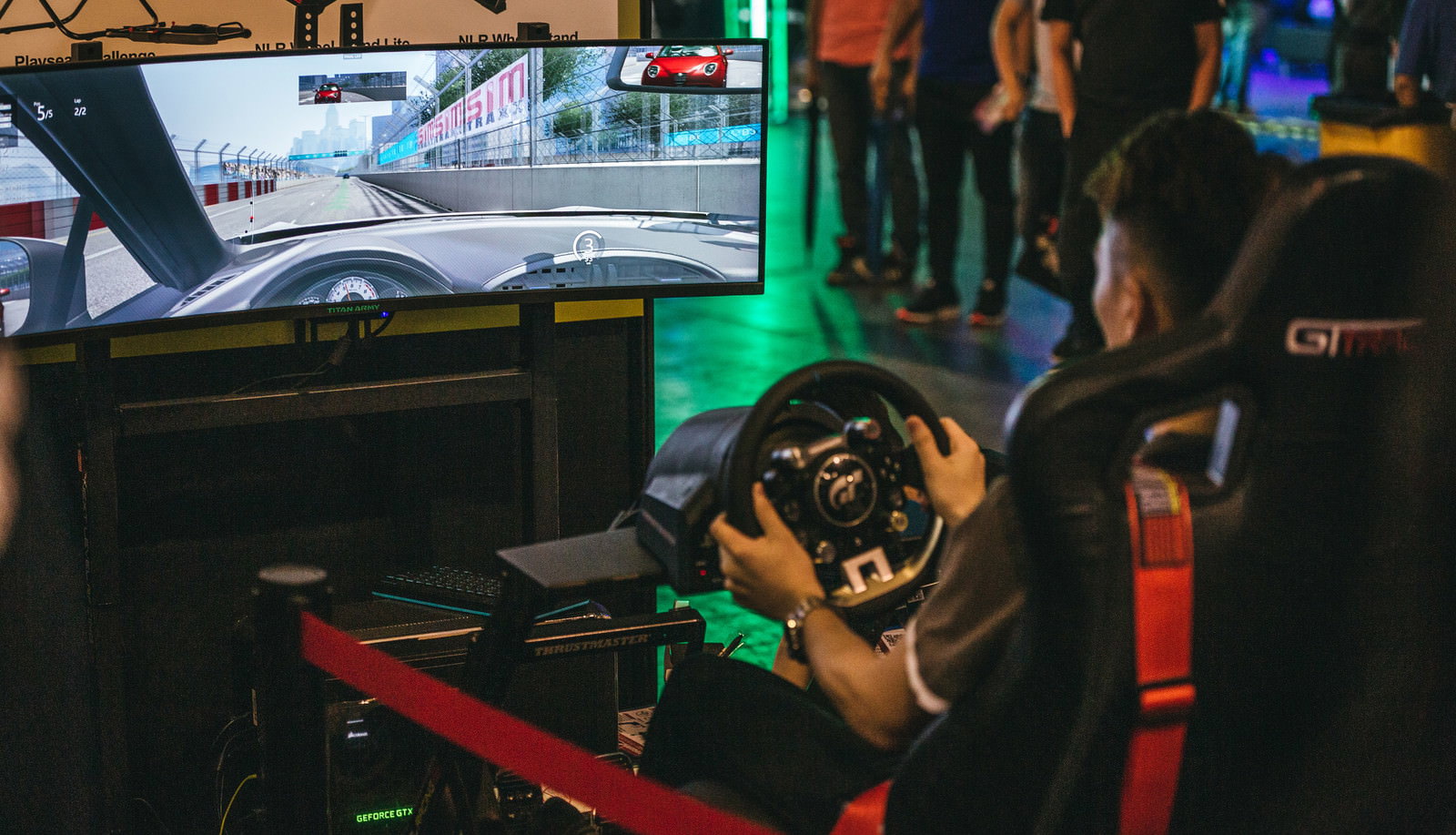 大画面モニターでレースゲームをプレイし、ハンドルを握る人