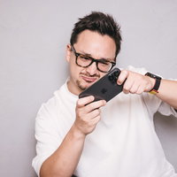 スマホゲームに熱中して体も揺れてしまう眼鏡の男子の写真