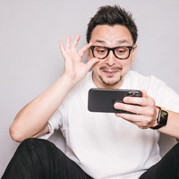 スマホを見てにやけるドイツ人ハーフの男性の写真