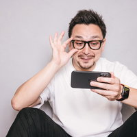スマホを見てニヤケる眼鏡をかけたドイツ人ハーフ男性の写真