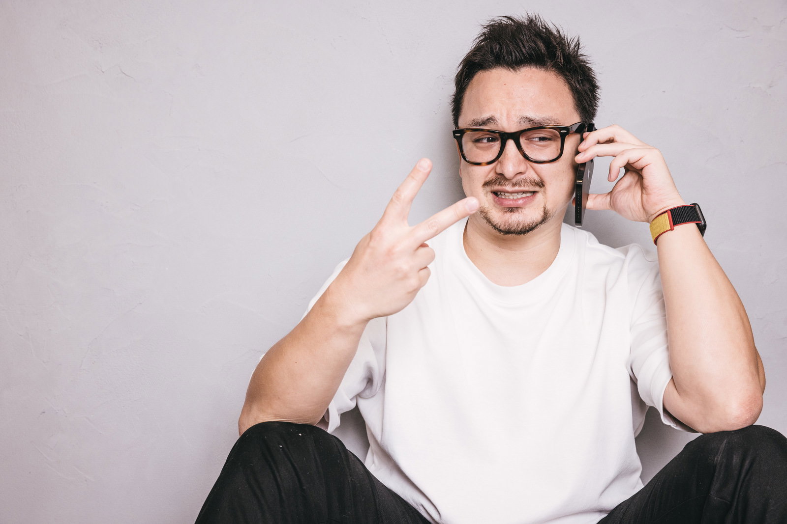 眼鏡をかけた白いシャツの男性がピースサインをして笑顔を見せている［モデル：Max_Ezaki］