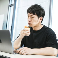 自分の動画を見ながらファミリーチキンを食べるユーチューバー男性の写真