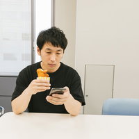 フライドチキン購入後に割引クーポンをスマホで見つけた男性の写真