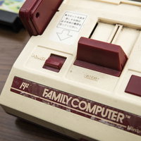 懐かしのファミコン本体とコントローラー、木目テーブルの写真