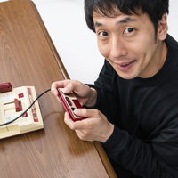 ファミコンのコントローラーを握る男性ゲーマーの写真
