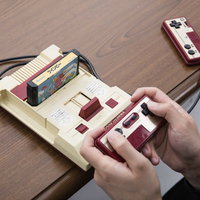 木目テーブルでファミコンのコントローラーを操作するゲーマーの子どもたちの写真