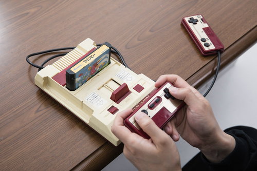 木目テーブルでファミコンのコントローラーを操作するゲーマーの子どもたち