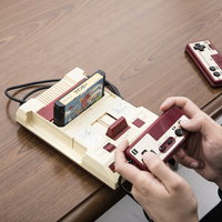 木製テーブルでファミコン風ゲーム機のコントローラーを握る大人たちの写真