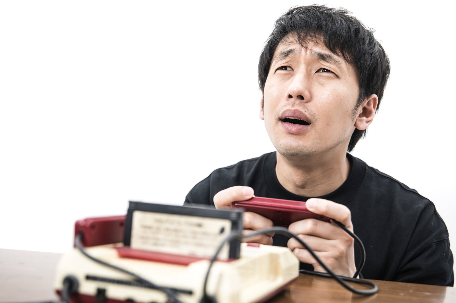ファミコンのゲームオーバーで悔しそうな表情の男性とゲームカセット［モデル：大川竜弥］