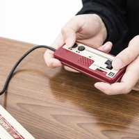 赤いファミコンの2コンで遊ぶ男性の手元のクローズアップの写真