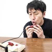 ファミコンの2コンに向かって叫ぶ男性とマイクの写真