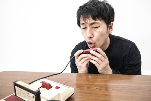 ファミコンの2コンに向かって叫ぶ男性とマイク