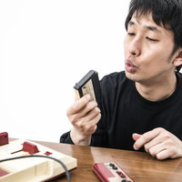 ファミコンカセットにフーフーと息を吹きかける男性の写真