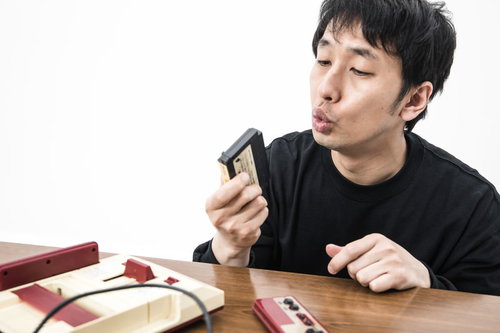 ファミコンカセットにフーフーと息を吹きかける男性
