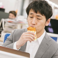 グレーのスーツ姿の男性がオフィスでフライドチキンにキスの写真