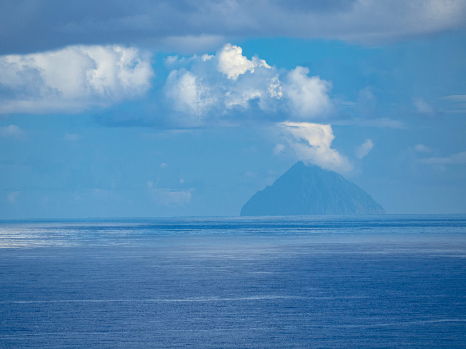 青い海と空の間に三角形のシルエットを見せる南硫黄島