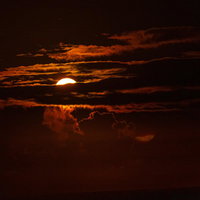 雲を輝かせて夜空に光の帯を流す月の写真