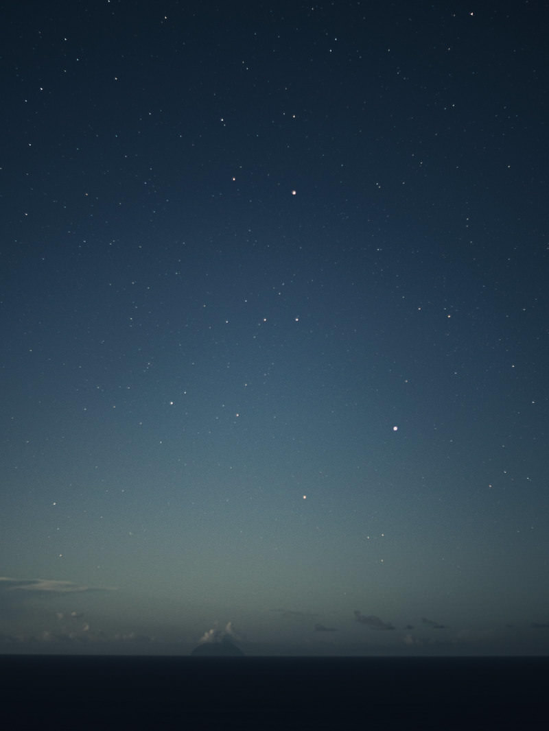 月夜の星空の下、水平線上に浮かぶ南硫黄島のシルエット