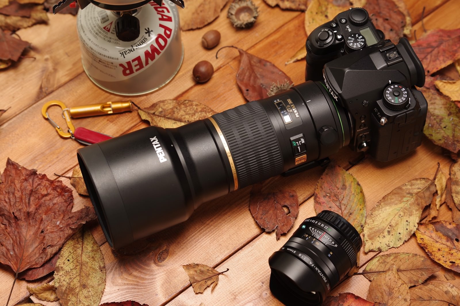 木製テーブルの落ち葉の上に置かれたPENTAX K-1MarkⅡと交換レンズ