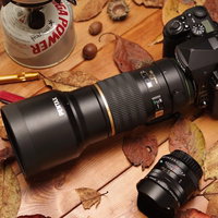 木製テーブルの上に置かれた替えのレンズとK-1MarkⅡの写真