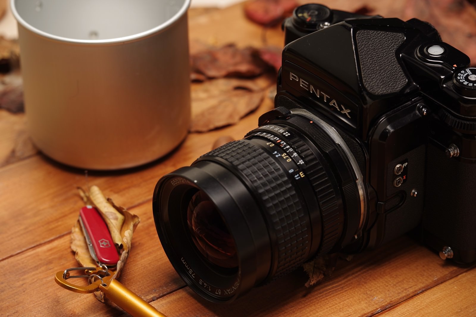 木製テーブルに置かれたPENTAX67と背景のマグカップ