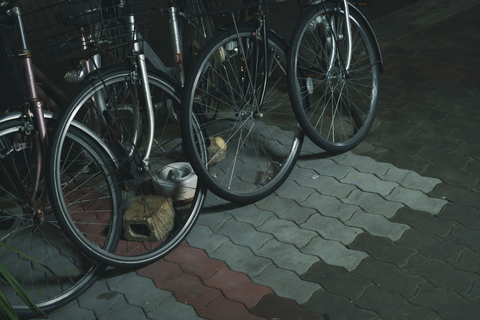 石畳の駐輪場に停められた複数の自転車の前輪部分